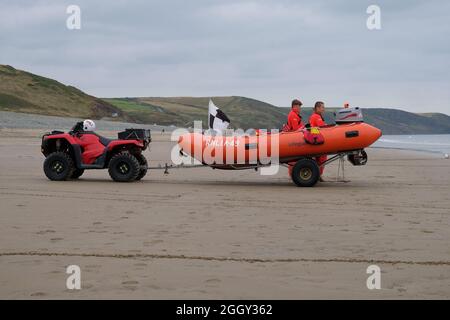 Newgale Pembrokeshire Galles 09.03.21 Sandy Beach. Imbarcazione semirigibile arancione su un rimorchio. Veicolo fuoristrada rosso. Due salvagenti. Scogliere della costa . Nero A. Foto Stock