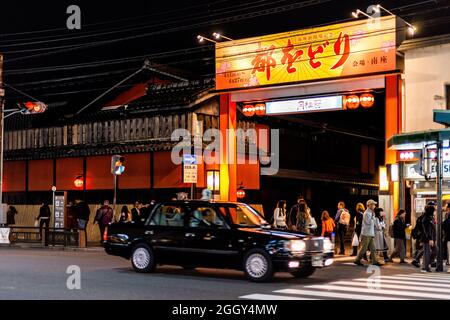 Kyoto, Giappone - 16 Aprile 2019: Famosa strada popolare di negozi arcade nel quartiere di Gion di notte con ingresso al cartello Hanamikoji Dori e taxi in b Foto Stock