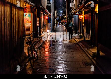 Kyoto, Giappone - 16 aprile 2019: Strada del quartiere di Gion sulla strada notturna con riflessione dopo la pioggia e la gente che cammina come vita notturna e poster geisha Foto Stock