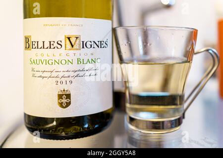 Miami Beach, USA - 19 gennaio 2021: Macrofumo di vino bianco francese Sauvignon blanc bottiglia con bicchiere di alcol versato sul tavolo di casa in cucina Foto Stock