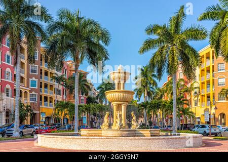 Napoli, USA - 24 luglio 2021: Bayfront residenziale strada condomini colorati edifici multicolore con fontana d'acqua da palme e blu Foto Stock