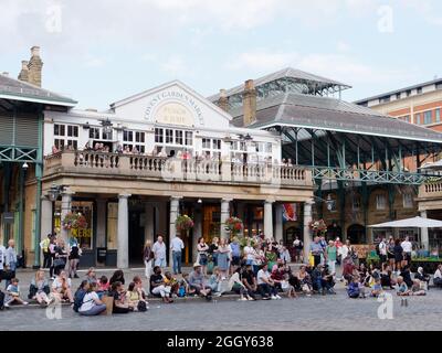 Londra, Greater London, Inghilterra, 24 2021 agosto: La folla si riunisce di fronte al mercato coperto e al pub Punch and Judy a Covent Garden. Foto Stock
