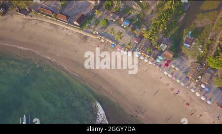 Drone shot di spiaggia pulita e bella paradiso in isola tropicale di Bali in Indonesia ancora sospeso sul mare con una vista agli ombrelloni o Foto Stock