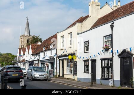 Vista della High Street nel villaggio di Chobham, Surrey, Inghilterra, Regno Unito, con le aziende e la chiesa di St Lawrence Foto Stock