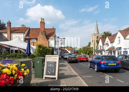 Vista della High Street nel villaggio di Chobham, Surrey, Inghilterra, Regno Unito, con le imprese, Il Sun Inn e la Chiesa di San Lorenzo Foto Stock