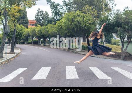 Ballerino balletto che fa una svolta acrobatica in strada su un attraversamento pedonale Foto Stock