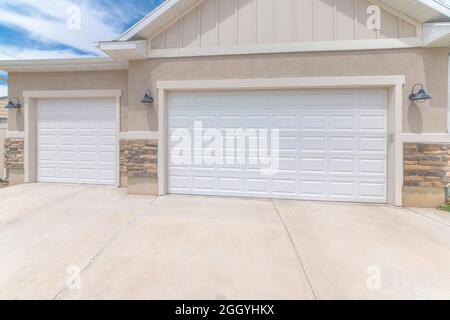 Esterno di un garage con porte bianche a doppia sezione e dispositivi di illuminazione a parete Foto Stock