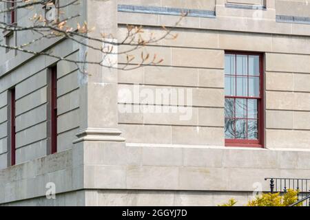 L'esterno di un muro di pietra calcarea vintage con finestre multiple. L'alto edificio governativo ha un cielo blu con le nuvole sullo sfondo. Foto Stock
