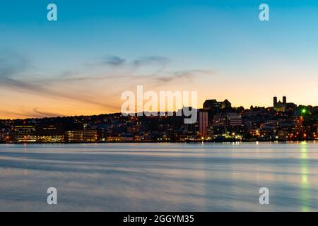 St. John's, Terranova, porto sul lungomare al tramonto. Le luci sull'acqua sono gialle e arancioni che si riflettono dallo skyline Foto Stock