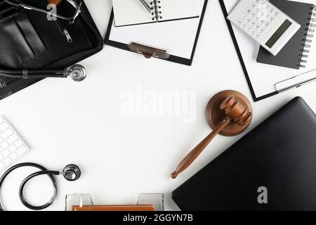 Concetto di legge medica. Gavel, taccuino e stetoscopio sul tavolo di vetro. Luce blu. Foto Stock