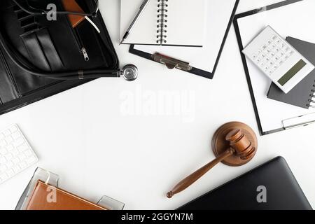 Concetto di legge medica. Gavel, taccuino e stetoscopio sul tavolo di vetro. Luce blu. Foto Stock