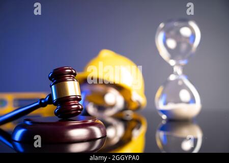Concetto di legge di costruzione. Casco e Gavel del giudice su sfondo grigio. Foto Stock