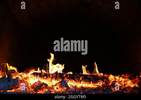 Scintille calde rosse che bruciano volano dal fuoco grande. Bel sfondo astratto sul tema del fuoco. Carboni brucianti, particelle infiammate che volano contro la colpa Foto Stock