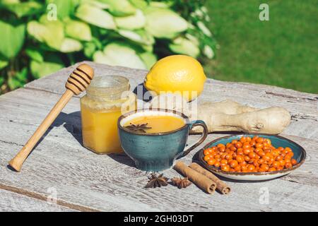 Tè di buckhorn di mare, miele, limone e zenzero su un tavolo di legno. Il tè anti-freddo è un antiossidante per la salute nella stagione influenzale Foto Stock