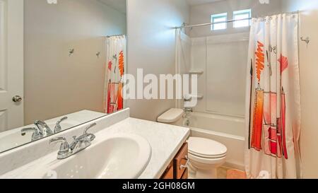 Pano interno di un bagno bianco con vasca combo doccia e lavandino singolo con specchio Foto Stock
