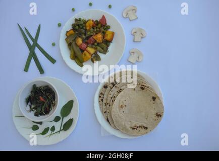 Indian Food: Piatto di matar paneer mix di verdure, saag (verdi) e roti (chapati) isolato su sfondo bianco Foto Stock