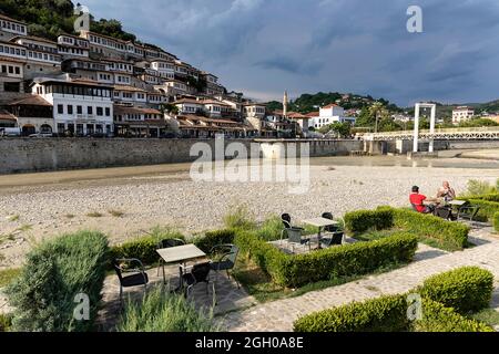 Gente del posto seduta in un giardino del ristorante locale vicino al fiume e la parte vecchia della città unesco di berat in albania Foto Stock
