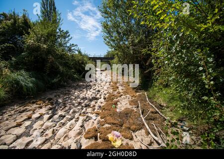 Il letto del fiume senza acqua, la siccità prende il suo pedaggio. Il letto del fiume è lastricato di pietre. Bridge sul canale. Foto Stock