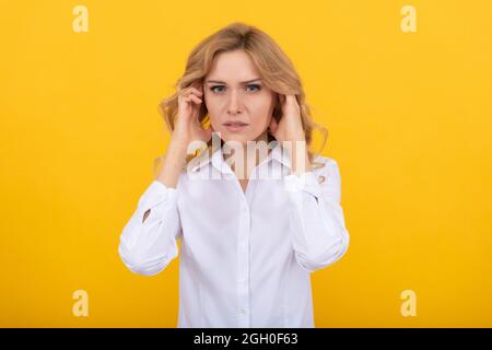 Malcontento donna toccare orecchie che soffrono di dolore orecchio sfondo giallo, orecchi Foto Stock