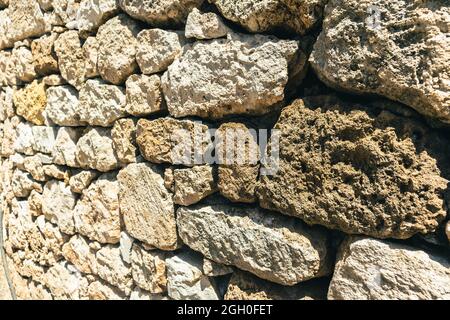 Primo piano di un muro di pietra marrone asciutto e ruvido all'aperto Foto Stock