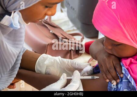 Operatore medico che effettua vaccinazioni di routine per i bambini in Africa Foto Stock