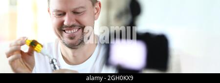 L'uomo sorridente riempie il vaporizzatore di marijuana per fumare e scatta foto Foto Stock