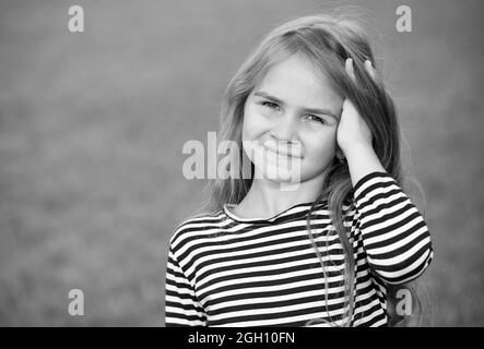 Sorridere bambino felice che scorre le dita attraverso lunghi capelli biondi paesaggio naturale estate, cura dei capelli, spazio copia. Bianco e nero. Foto Stock