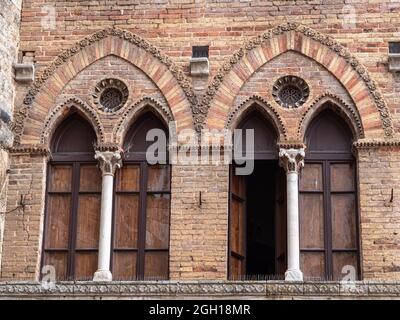 Particolare di due finestre in un edificio con mattoni a vista nella città medievale toscana di San Gimignano - Italia. Foto Stock