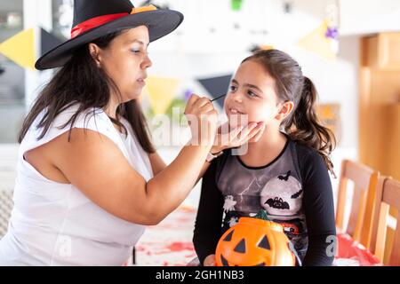 Madre che fa il trucco della sua figlia per partito di Halloween. Foto Stock