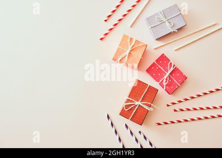 Diverse confezioni regalo colorate vacanza avvolte in carta colorata e archi su sfondo beige. Foto Stock