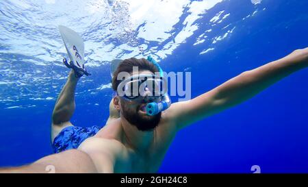 un uomo impegnato nello snorkeling non è sul mare rosso e mostra gesti diversi con le sue mani Foto Stock