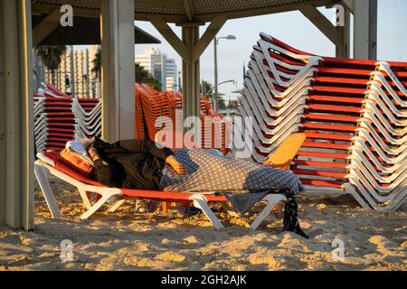 Una donna che dorme su una sdraio sulla spiaggia di Tel Aviv, Israele, all'alba. Foto Stock