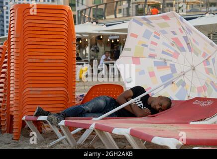 Tel Aviv, Israele - 16 agosto 2021: Un giovane che dorme sulla spiaggia di Tel Aviv, Israele, all'alba. Foto Stock