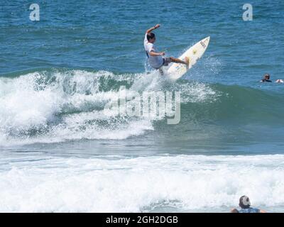 surfisti che prendono onde e si manovrano in mare in una limpida giornata estiva. Foto Stock