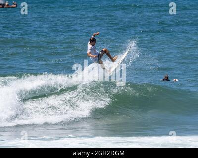 surfisti che prendono onde e si manovrano in mare in una limpida giornata estiva. Foto Stock