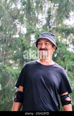 Uomo attivo e sorridente asiatico che fa sport nel parco. Foto Stock