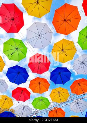 Ombrelloni a tema autunnale appendono sopra il vicolo del parco. Ombrelloni colorati appesi sopra gli alberi del parco Foto Stock