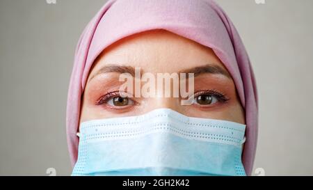 Primo piano occhi di donna musulmana che indossa maschera medica Foto Stock