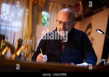 Artista che lavora in studio. Uomo di mezza età che fa opere d'arte creative, dipingendo in acquerello con pennello. Foto Stock