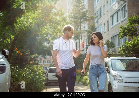 Giovani, Millennial, camminando lungo una strada cittadina in abiti estivi e parlando con passione. Foto Stock