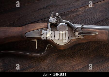 antico muschio di flintlock del xvii secolo con fiasca di polvere e pallottole a led su ponte di legno. Foto Stock