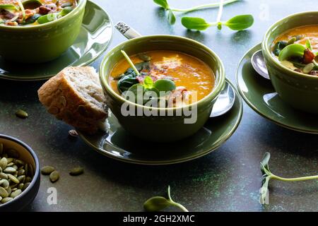 Primo piano di una ciotola di zuppa di zucca di butternut servita con pane di semi di zucca crudi. Foto Stock