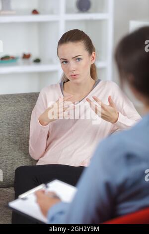 psicologa femminile che prende appunti durante la terapia psicologica Foto Stock