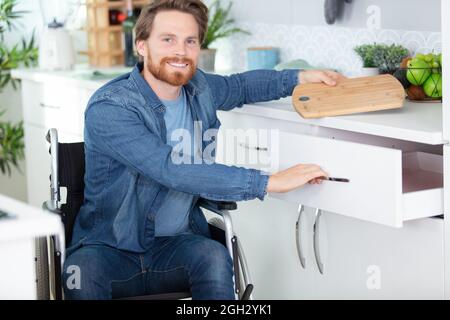 giovane disabili in cucina su sedia a rotelle Foto Stock