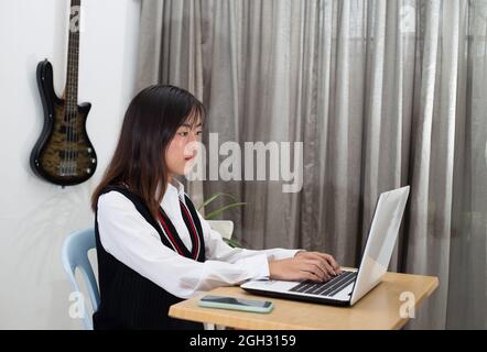 Giovane donna malese seduta alla sua scrivania e al lavoro Foto Stock