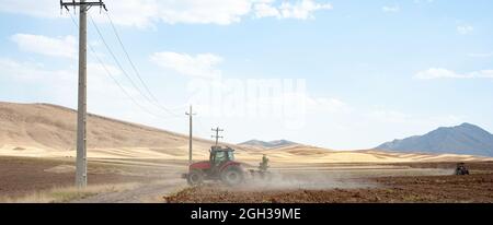 Vecchio trattore che lavora sul campo arato, campo di grano, in iran Foto Stock