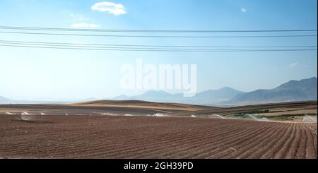 file di suolo prima di piantare. Solchi modello di fila in un campo arato preparato per piantare raccolti in estate in iran. Annaffiando il campo di grano arato Foto Stock