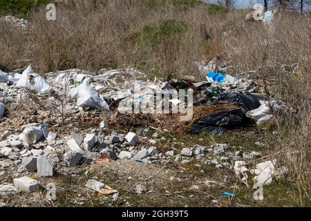 Cosparsi di campi di spazzatura e strade. Caminetti da rifiuti e pneumatici ruote. Plastica, polietilene, bottiglie, sacchetto per la casa e la costruzione Foto Stock