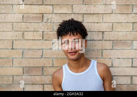 Afro latino maschio adolescente sorridente contro un muro Foto Stock