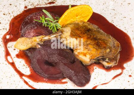 Gamba d'anatra con pera ubriaco nella composizione con vino sul tavolo. Foto Stock